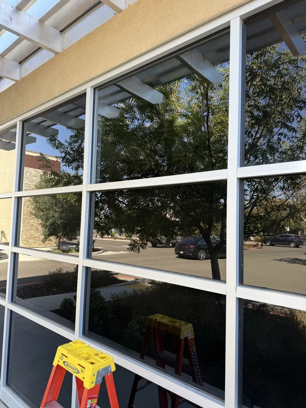 A multi-pane commercial window wall reflecting the sky and street.