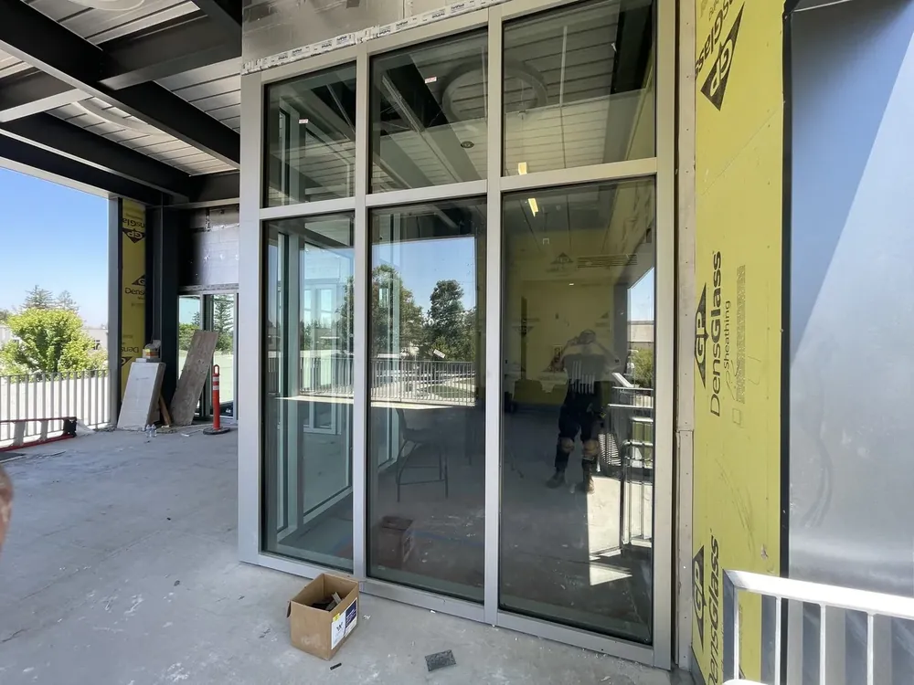 A commercial glass storefront entrance with aluminium framing and sliding panels.