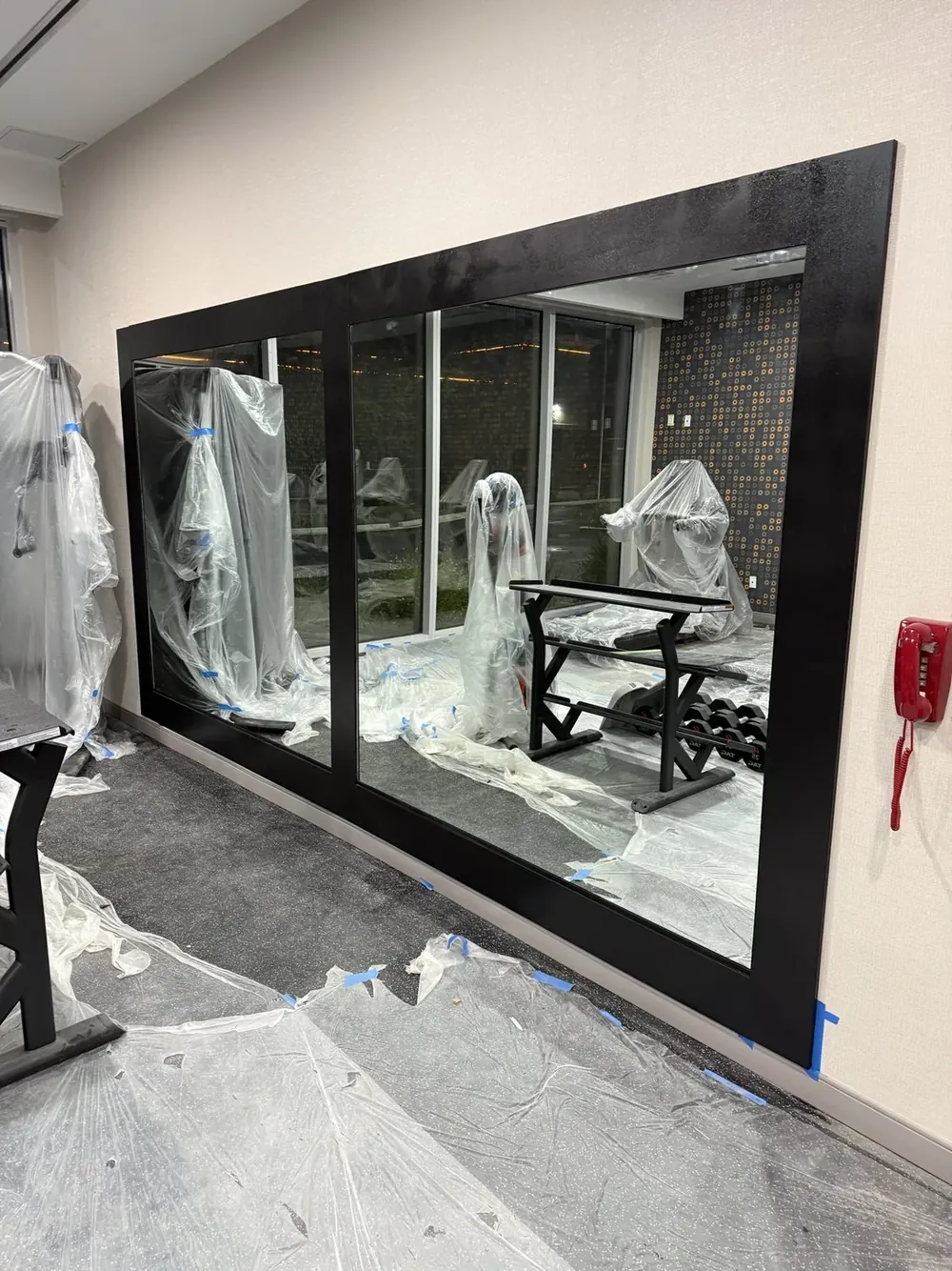 A large black-framed interior glass wall with a sliding glass door during a build out.