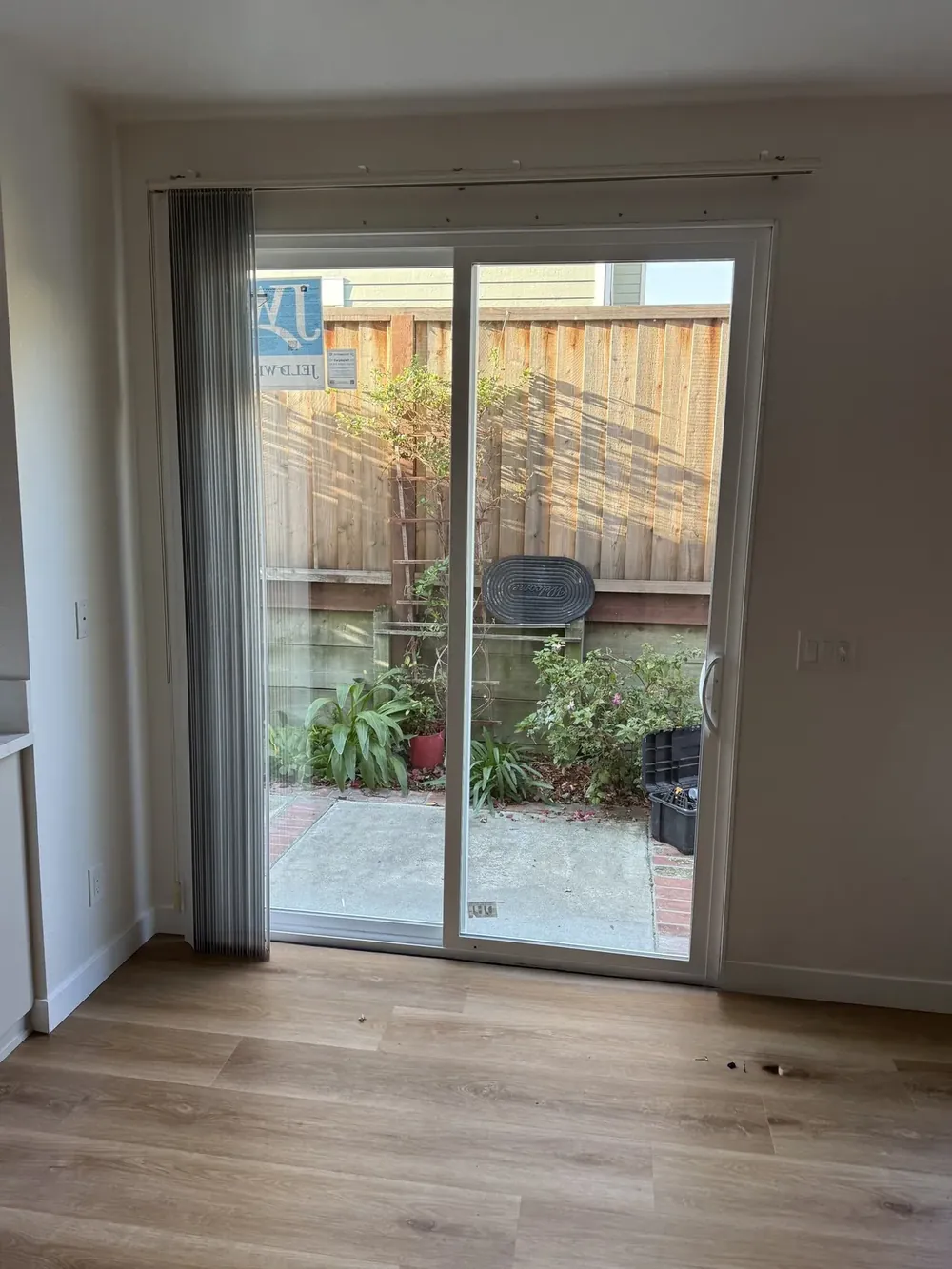 A white-framed sliding glass patio door opening from a room to a backyard.