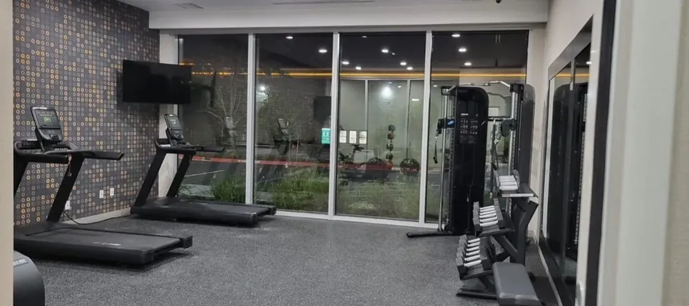 Floor to ceiling mirror panels along the wall of a home gym with fitness equipment.